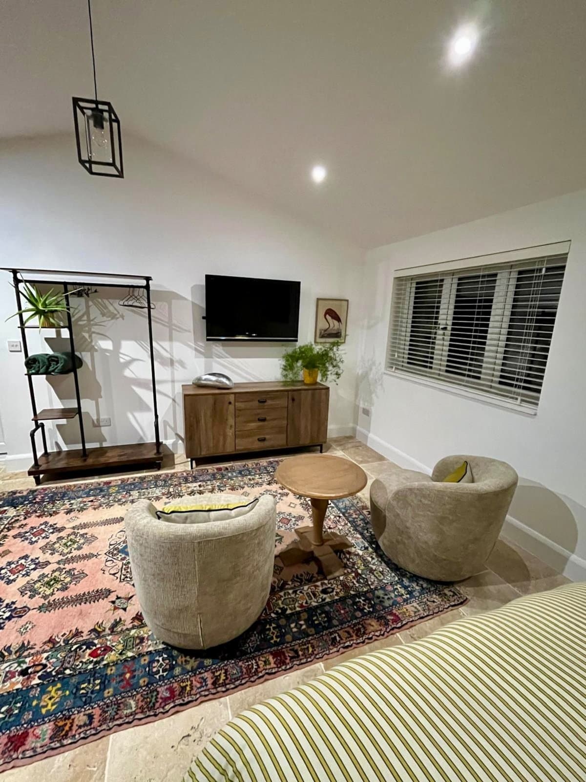 The studio's sitting area: two swivel chairs on a patterned rug, a TV and a vaulted white ceiling