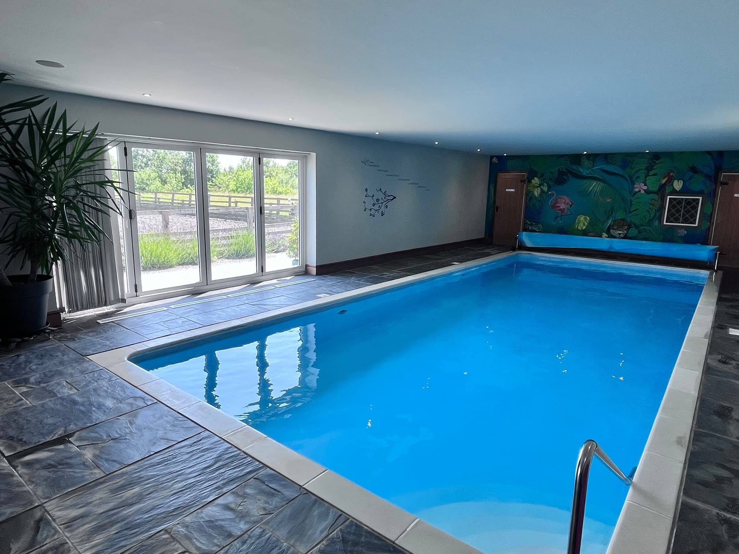 The heated indoor pool, with slate tiles round the edge and glass doors out to the fields